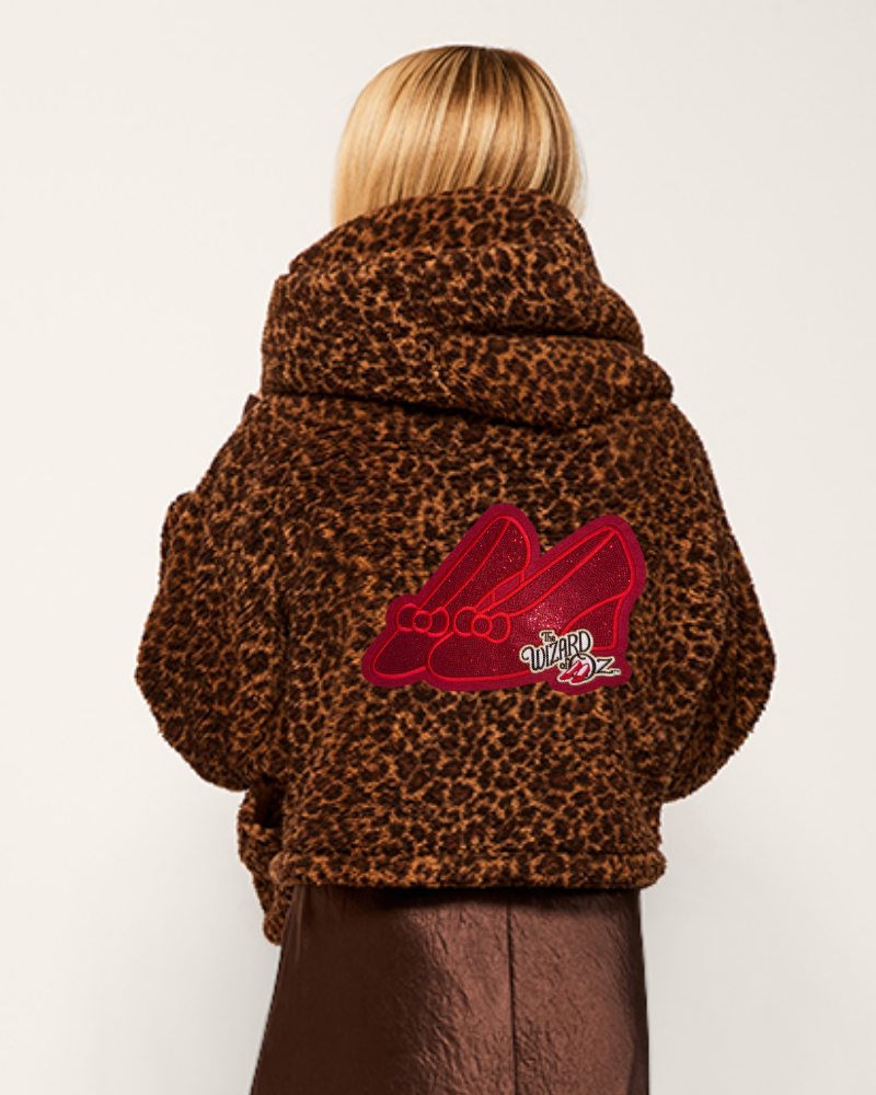 Person wearing a leopard print jacket with a red logo on the back against a white background