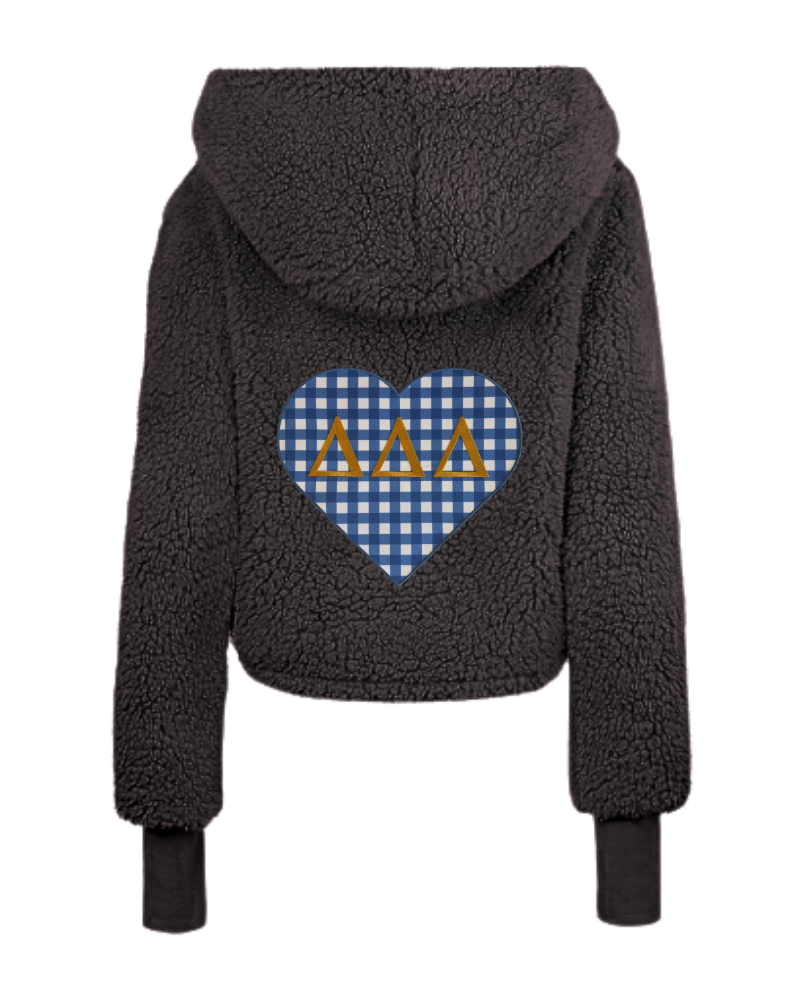 A black sherpa fleece cropped hoodie shown from the back, featuring a blue and white gingham heart graphic with three gold Greek letters (Delta Delta Delta) in the center.
