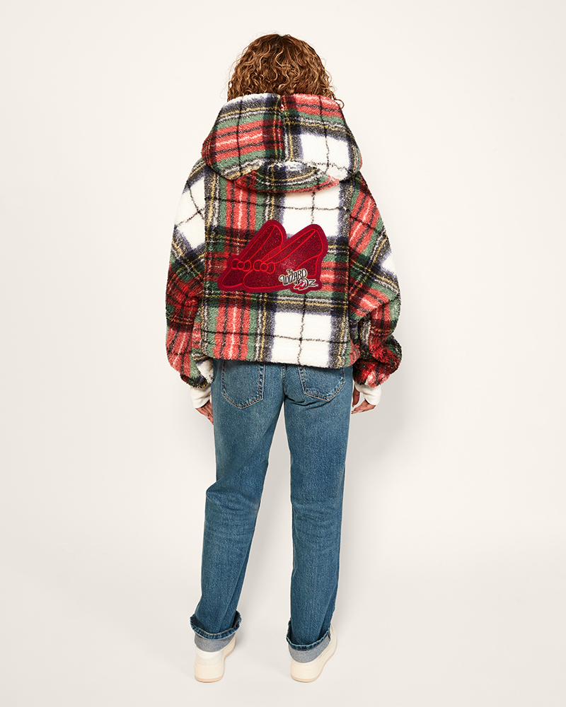 Person wearing a plaid jacket with a red heart design on the back, standing against a white background.