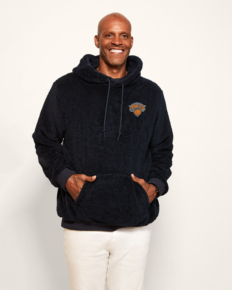 man wearing navy hoodie with new york knicks embroidered logo in upper left chest