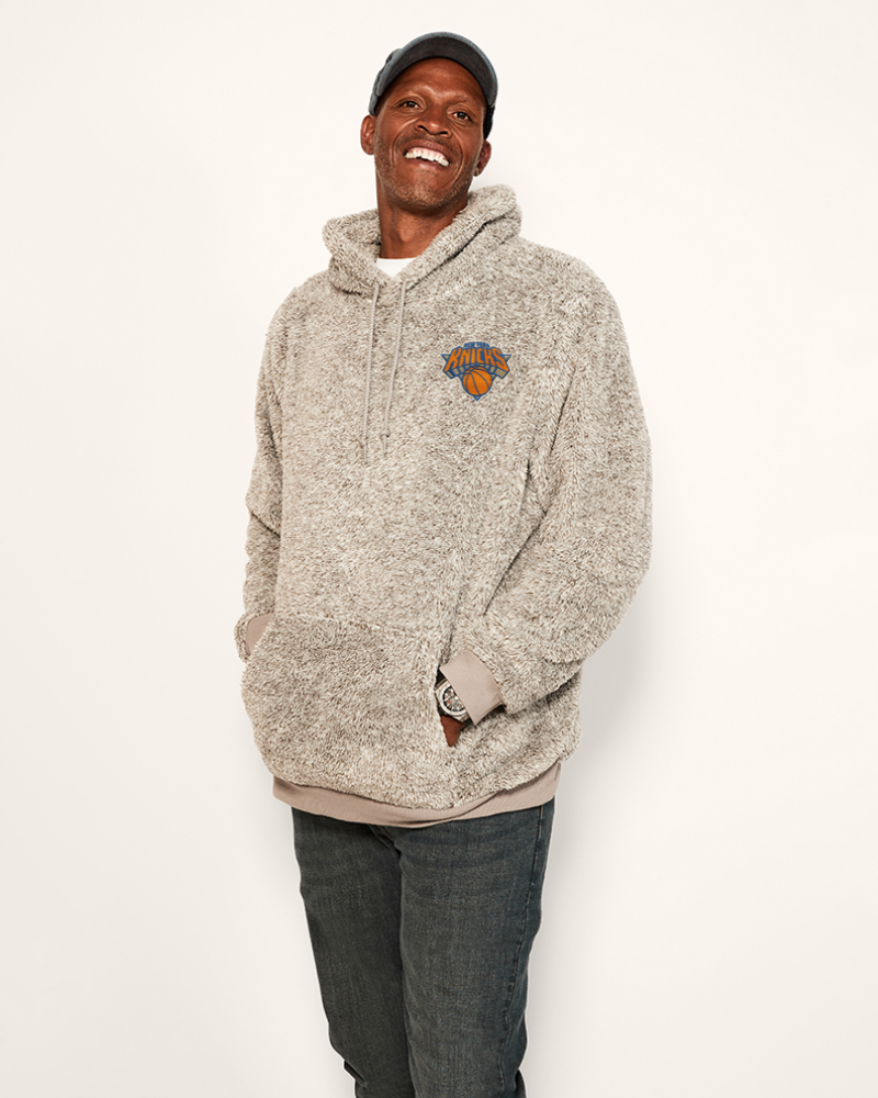 man wearing grey hoodie with embroidered new york knicks logo in upper left chest