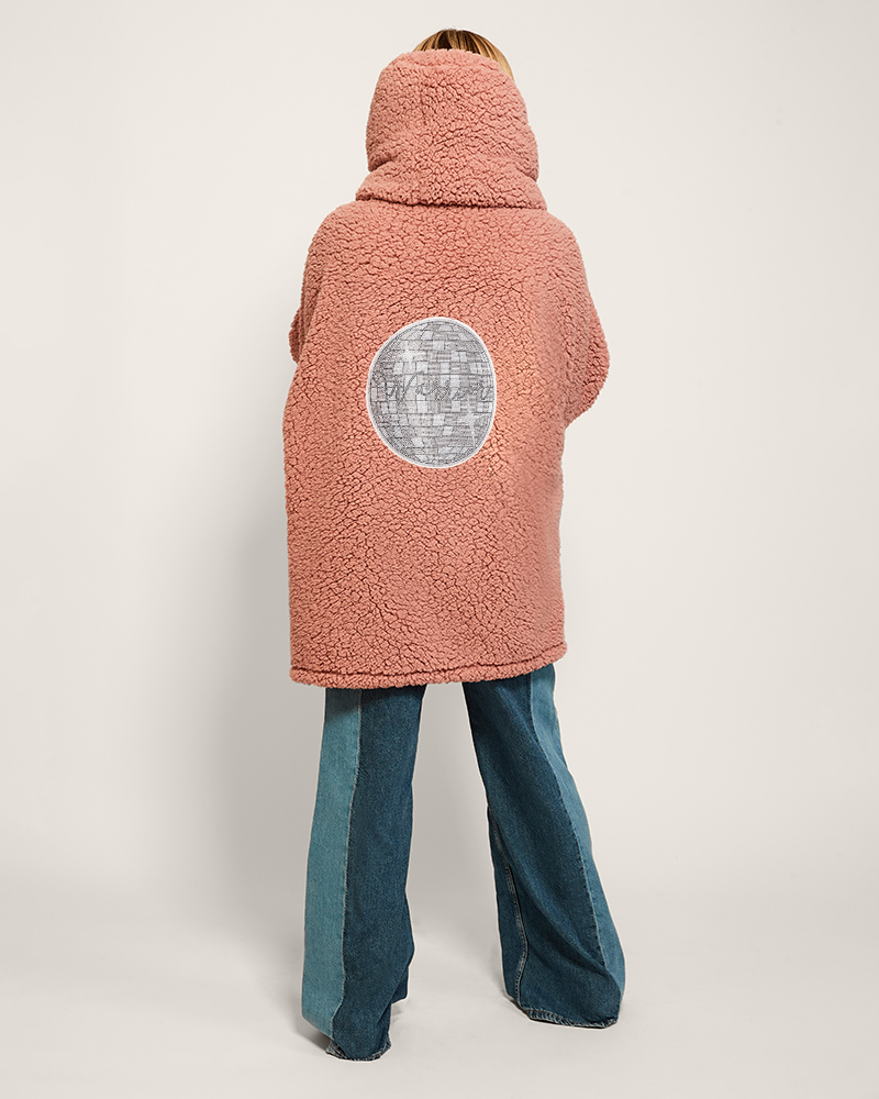 Person wearing a pink fleece jacket with a bedazzled disco ball design on a white background