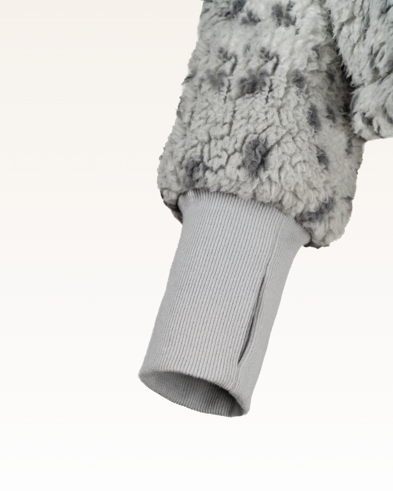 Close-up of a textured gray garment with ribbed cuffs on a white background