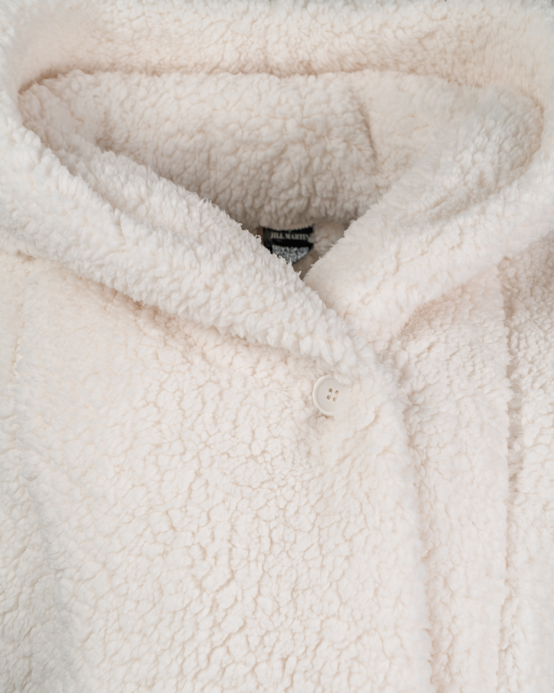 Close-up of a textured ivory sherpa fabric with a button closure