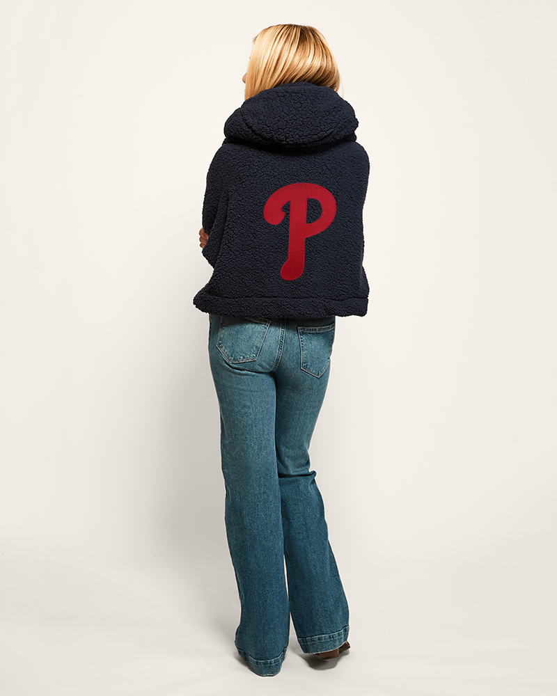Person wearing a navy lounger hoodie with a red phillies logo on the back, standing against a white background
