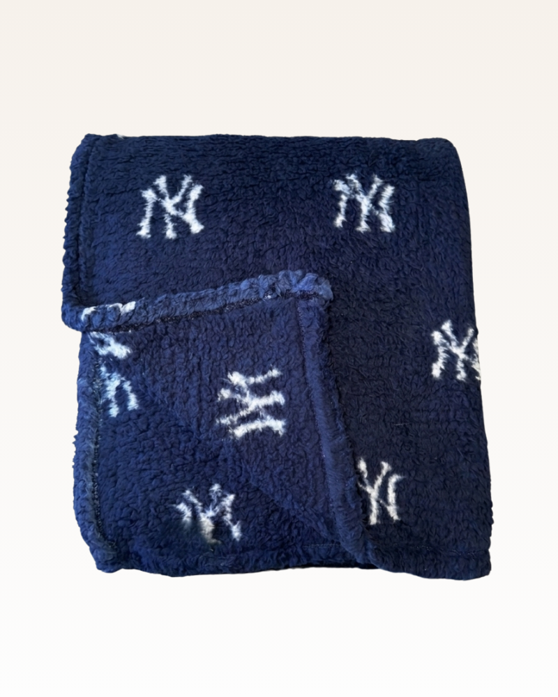 Navy blue towel with white 'NY' logo pattern on a light gray background