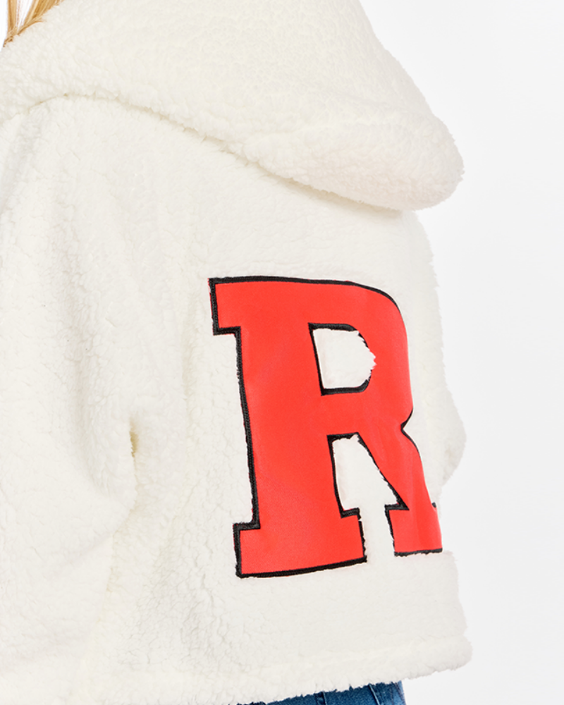 Close-up of a cream sherpa fleece hoodie featuring a large red block letter 'R' outlined in black on the back, with a small portion of blue jeans visible at the bottom.