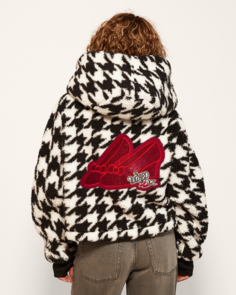 Person wearing a houndstooth pattern jacket with a red logo on the back against a white background