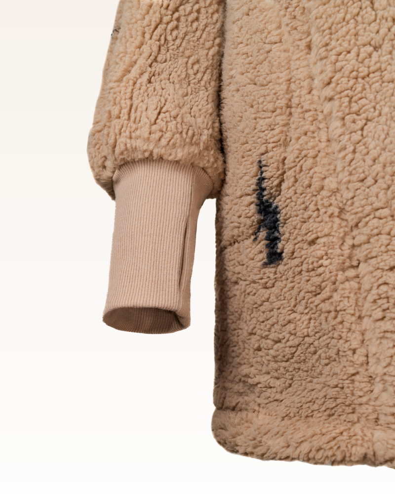 Close-up of a beige sherpa jacket with lightning bolts on a white background