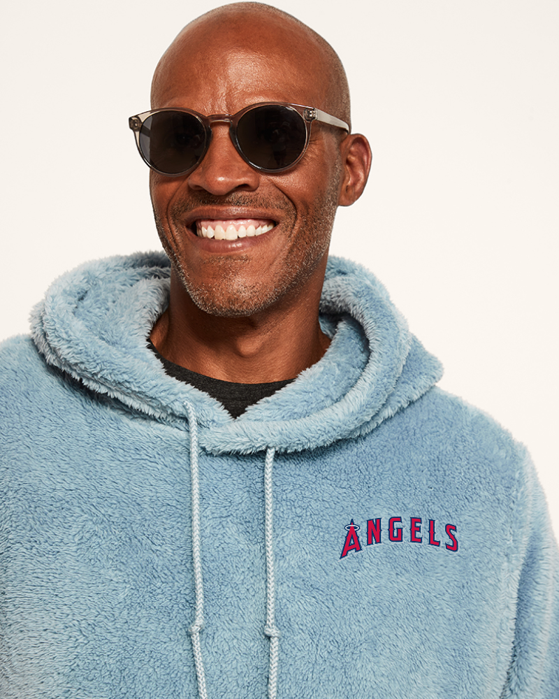 Man wearing a light blue sherpa hoodie with a los angeles angels logo on a white background