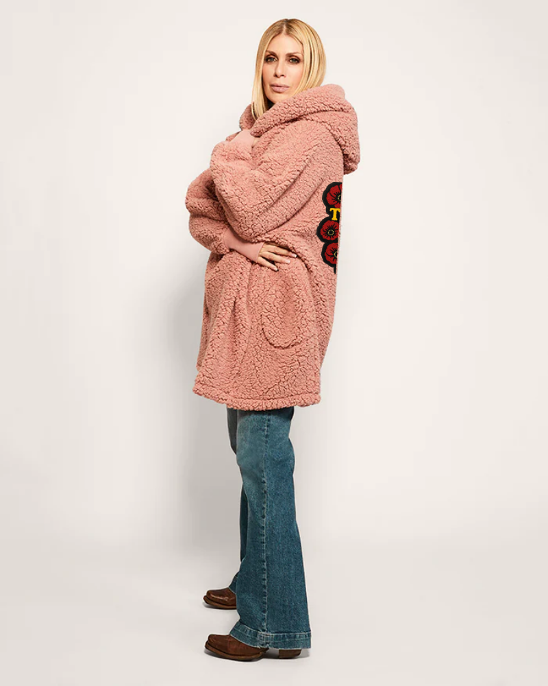 Woman wearing a pink hooded coat with a floral design on a white background