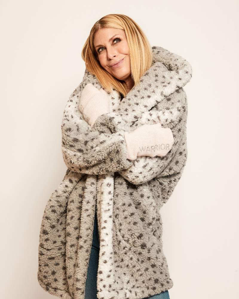 Woman wrapped in a large gray and white patterned blanket with 'Warrior' text on a plain background