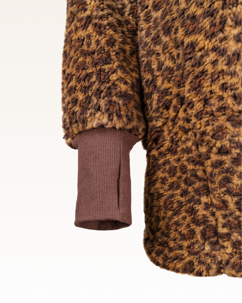 Close-up of a brown and black leopard print sherpa with a ribbed brown trim on a white background.