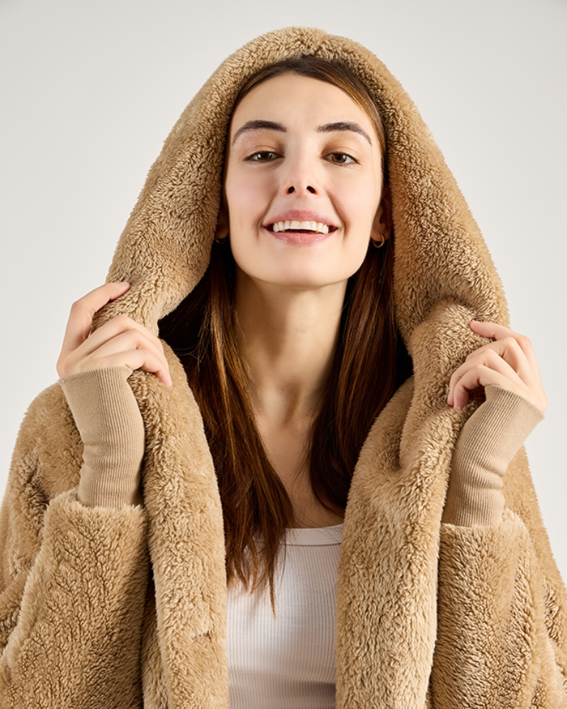 Woman wearing a beige fleece jacket with the hood up on a plain background
