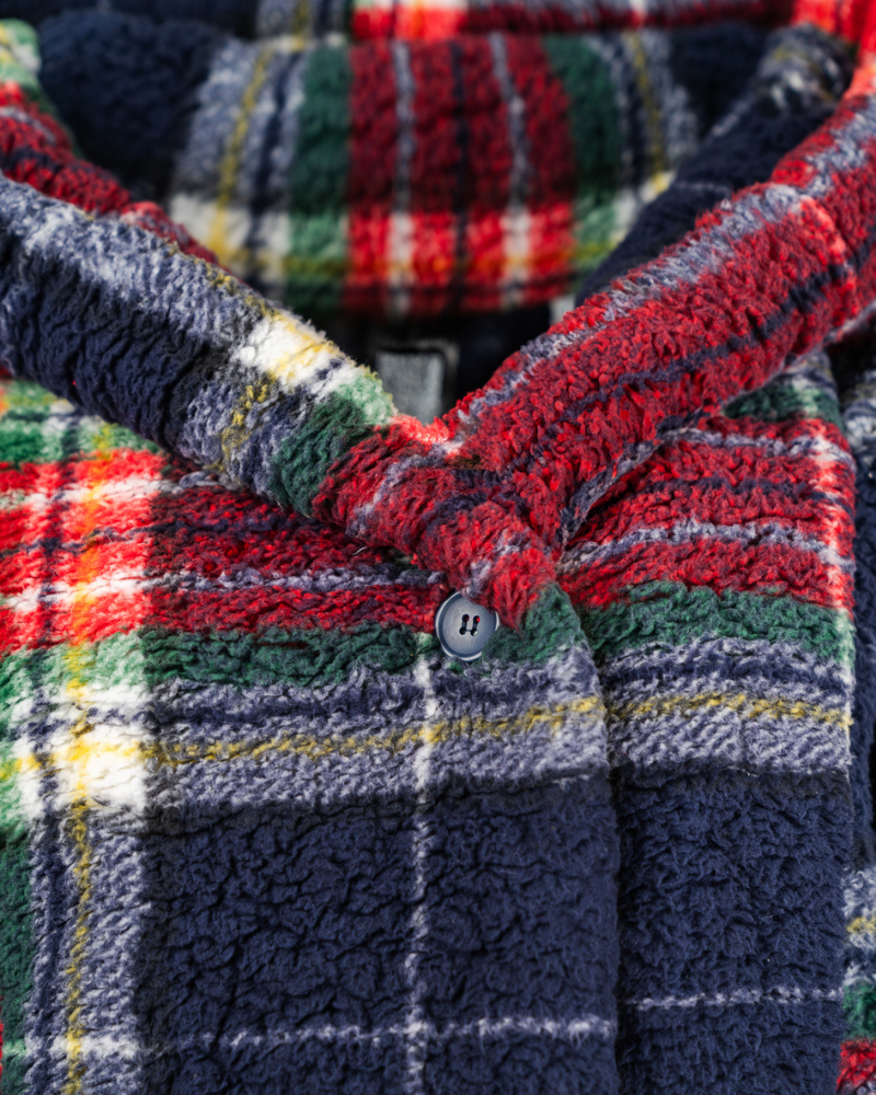 Close-up of a plaid jacket with a button, featuring red, green, and blue colors.