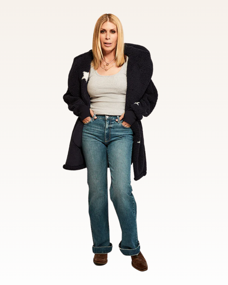 Woman wearing a black coat, white shirt, blue jeans, and brown shoes on a white background