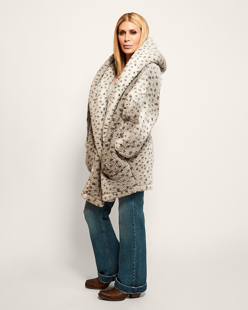 Woman wearing a patterned coat and jeans on a white background