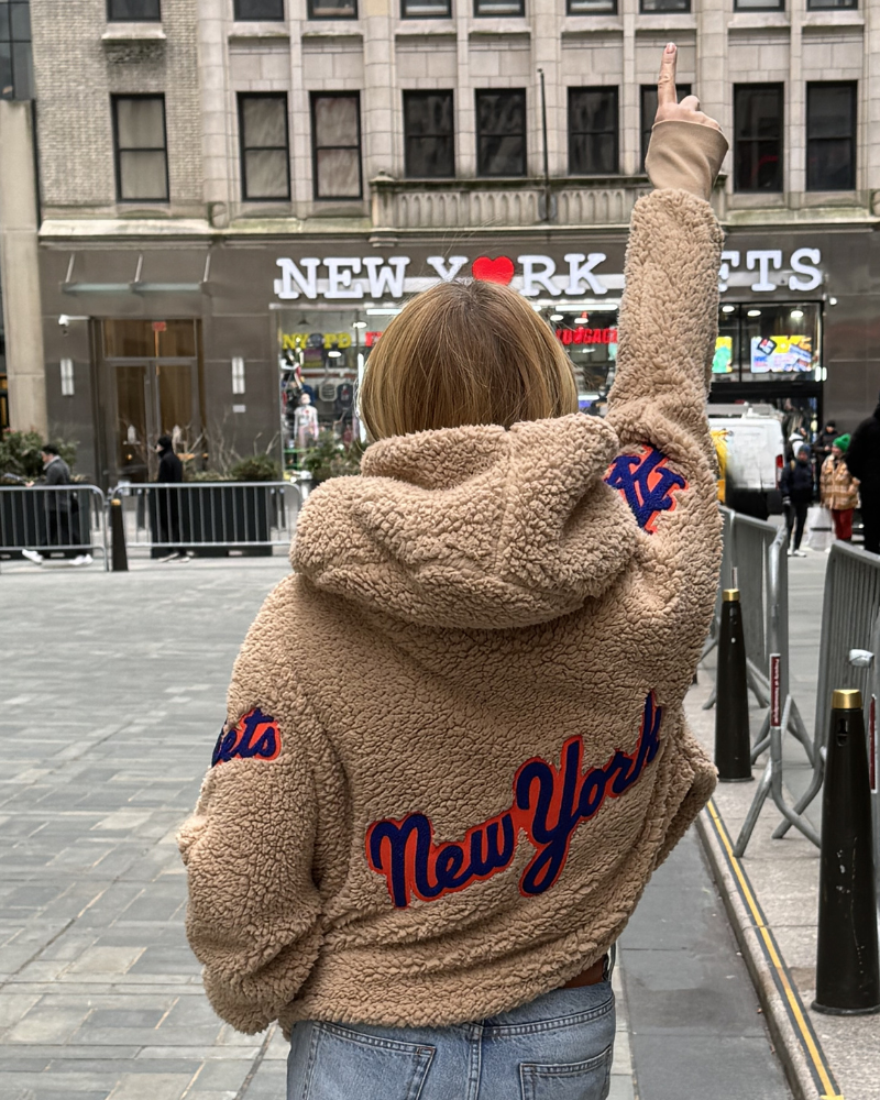 Person wearing a beige sherpa jacket with 'New York' text in an urban setting|Jill: 5'6" in size XS/S