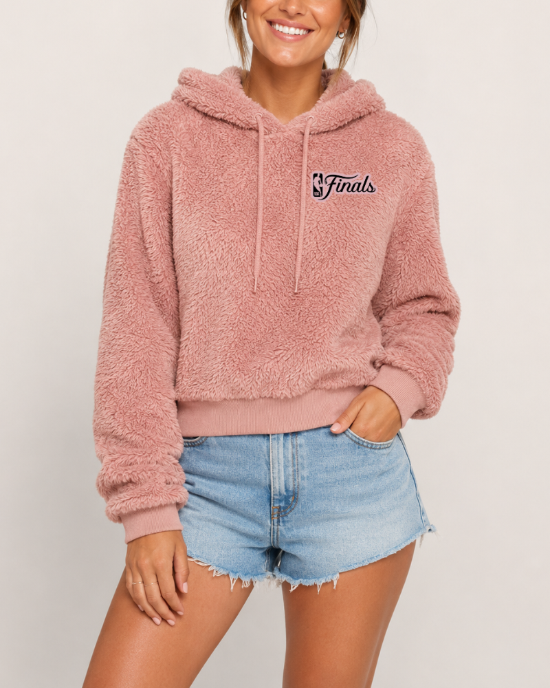 Person wearing a pink fleece hoodie with 'Finals' text and denim shorts on a plain background