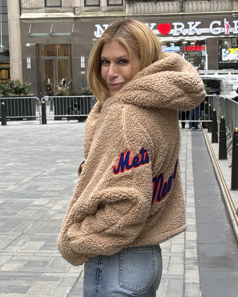 Person wearing a beige fleece jacket with 'Mets' and 'New' text, standing on a city street.|Jill: 5'6" in size XS/S