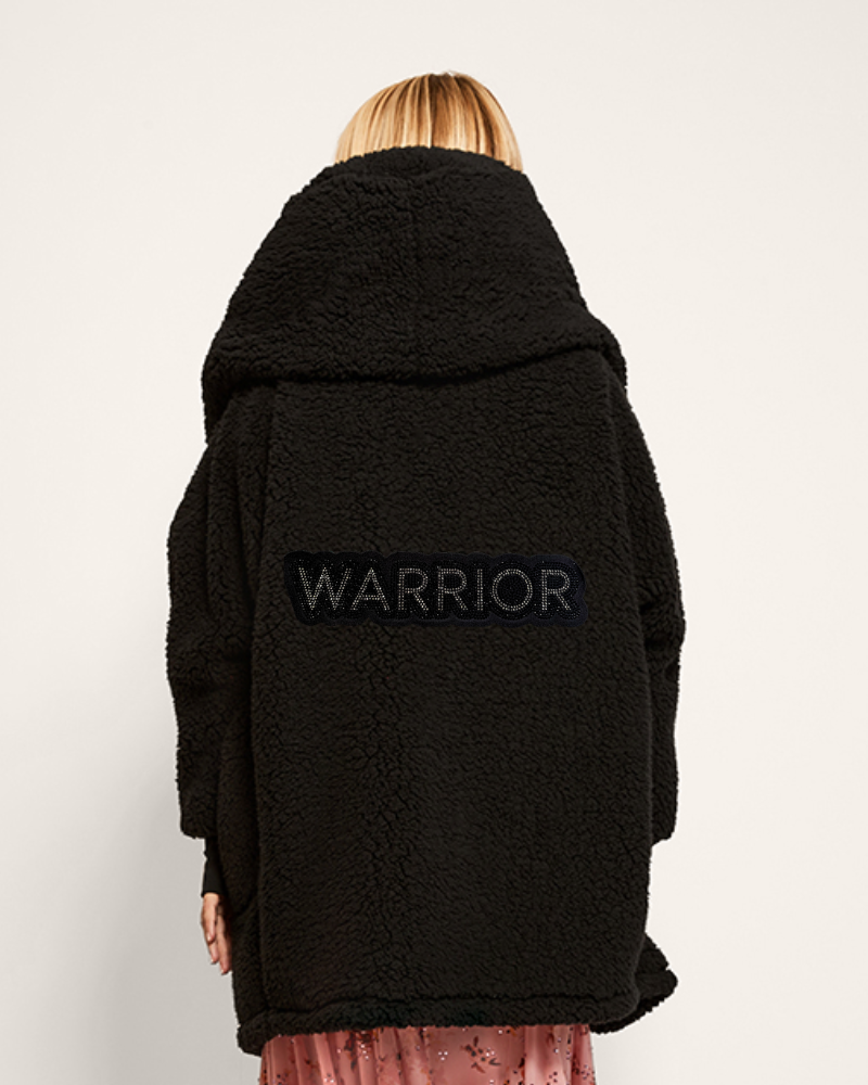 Person wearing a black coat with 'WARRIOR' text on the back against a white background