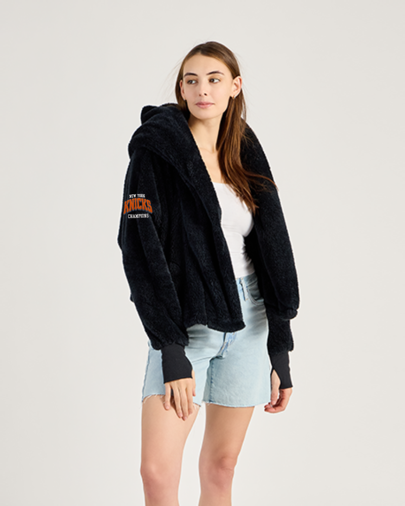 Woman wearing a black lounger jacket with branding on a white background