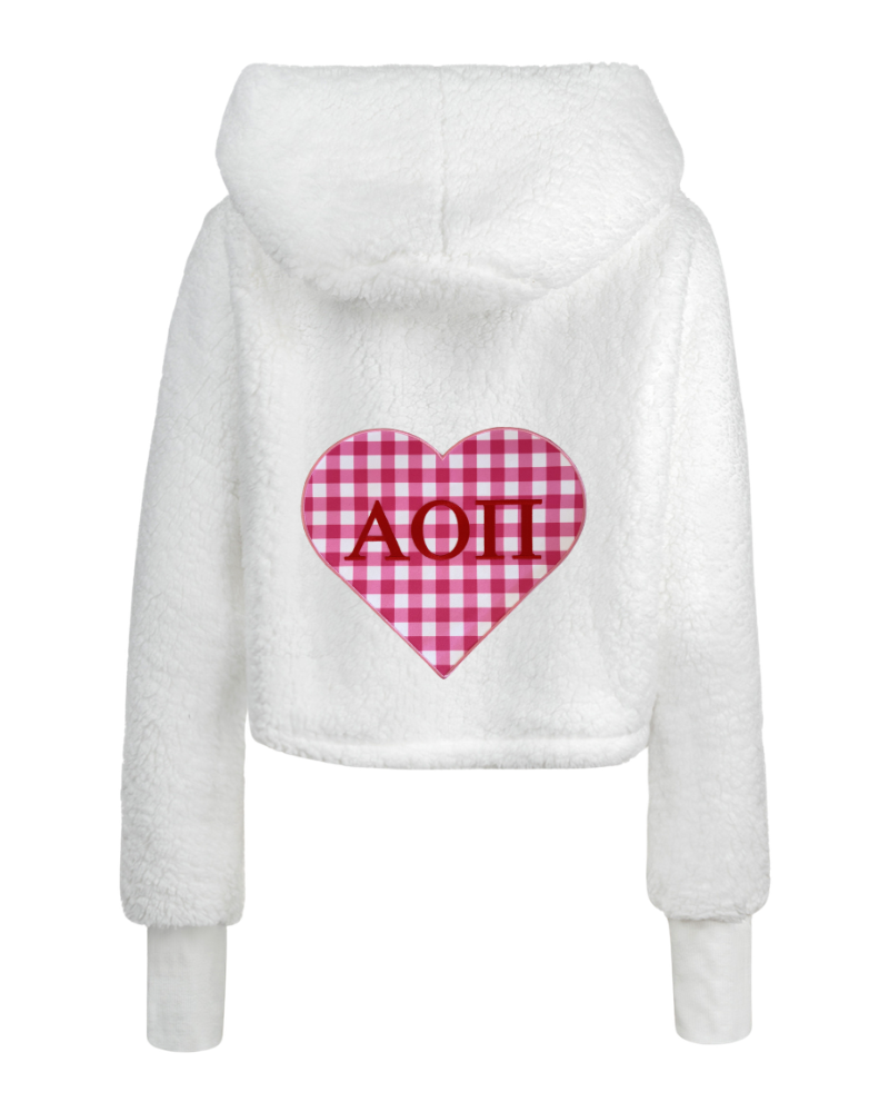 White fuzzy cropped hoodie with a pink and red gingham heart graphic on the back featuring the letters 'Alpha Omicron Pi' in red.