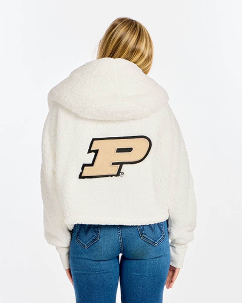 A woman viewed from behind wearing a cream sherpa cropped hoodie with a large Purdue 'P' logo on the back, paired with blue jeans, against a plain white background.