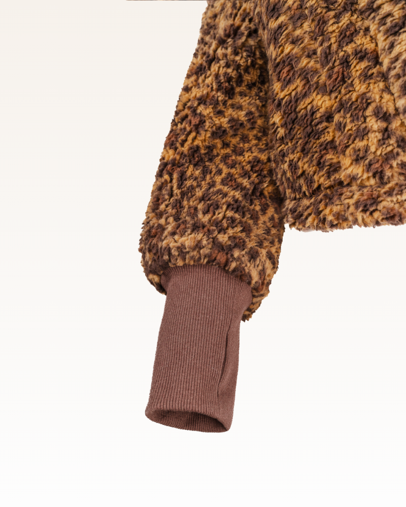 Close-up of a brown and black leopard print fabric with a brown ribbed trim on a white background.
