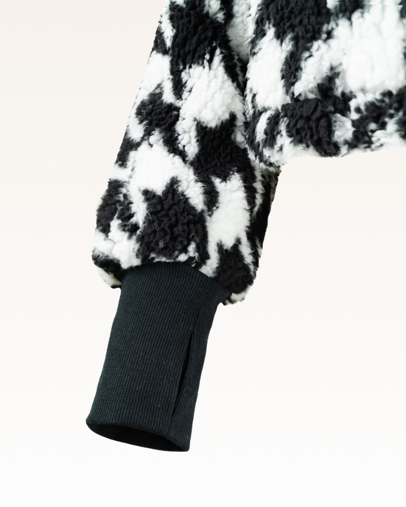 Close-up of a black and white checkered garment with a dark ribbed trim on a light background