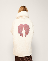 Person wearing a white coat with pink angel wings design on the back against a plain background