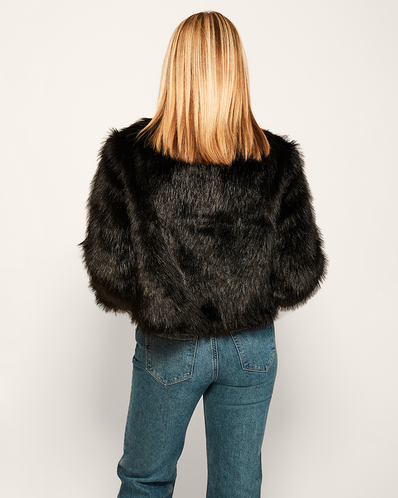 Person wearing a black fur coat and blue jeans on a white background