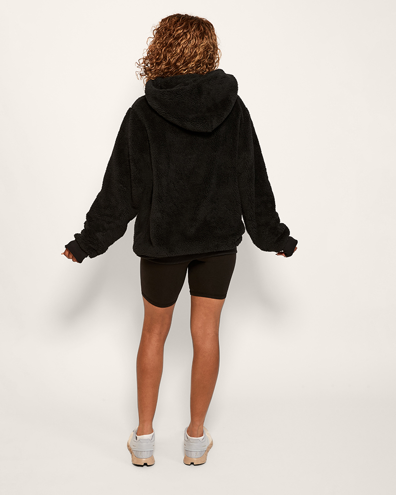 Person wearing a black hoodie and black shorts on a white background
