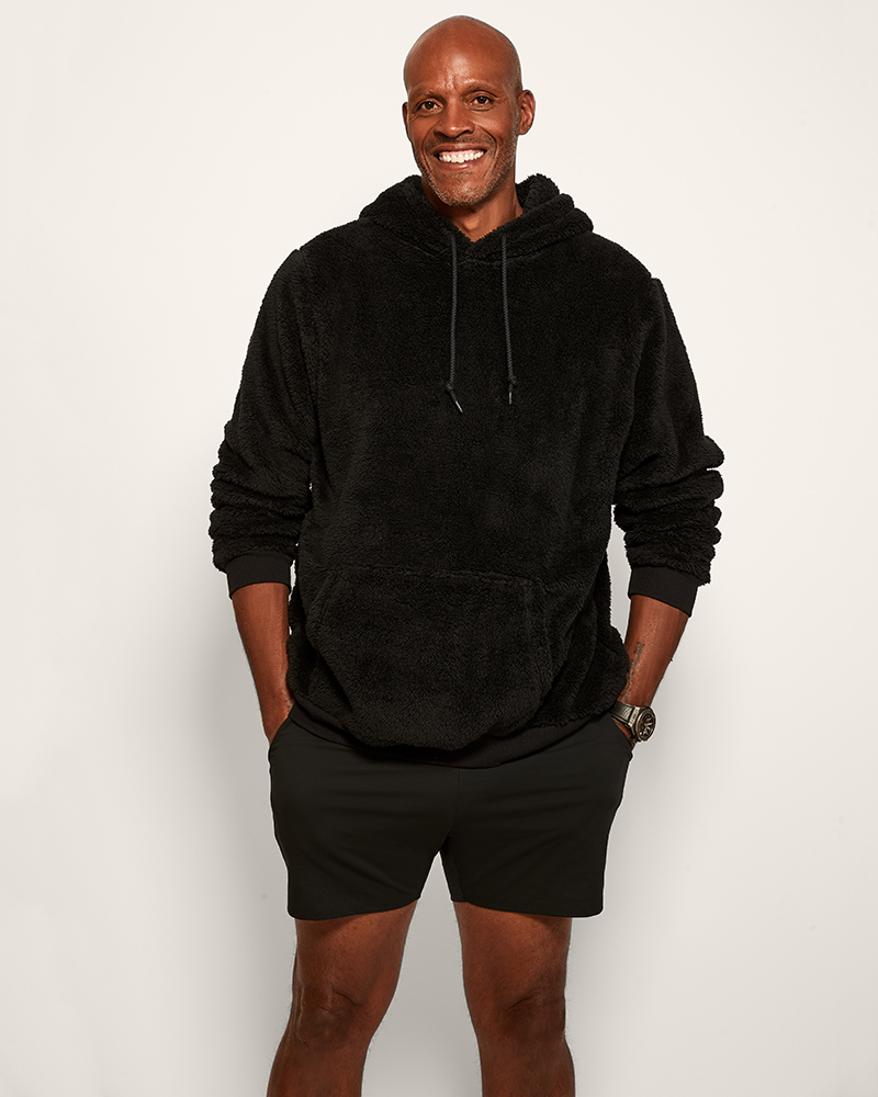 Man wearing a black hoodie and shorts on a white background