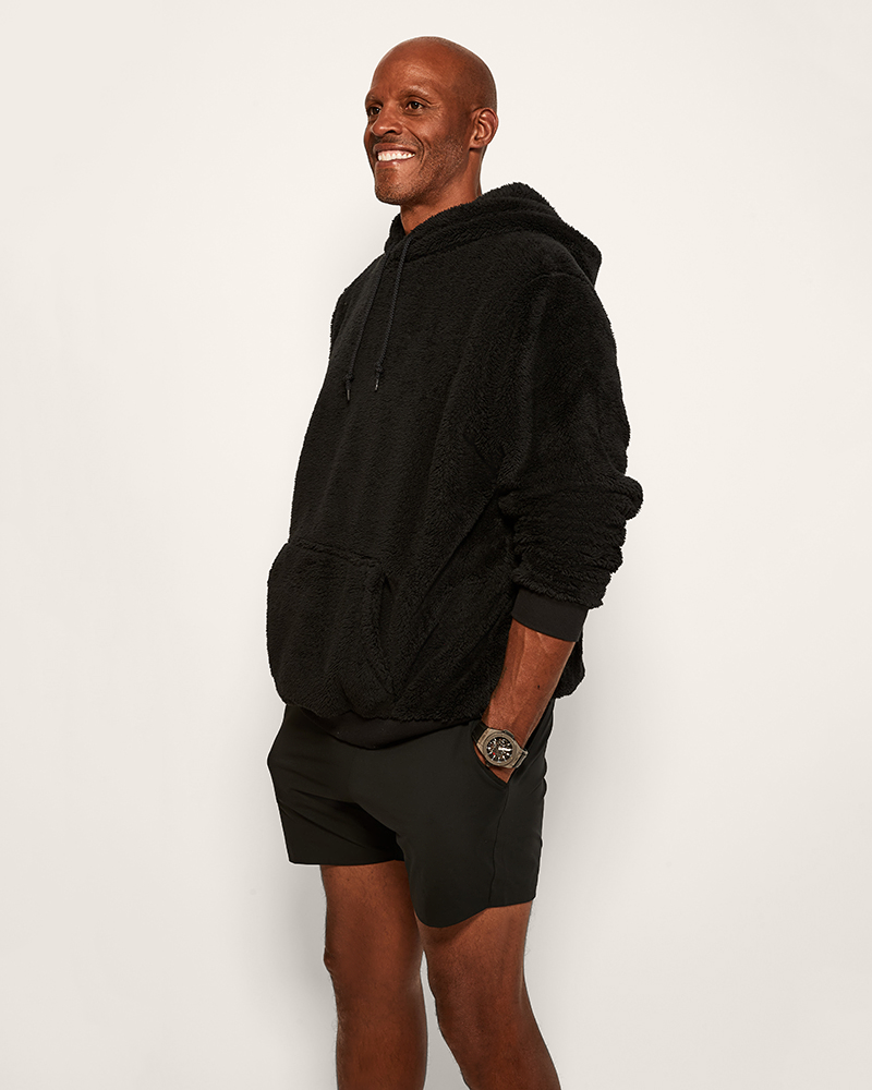 Man wearing a black hoodie and shorts on a white background