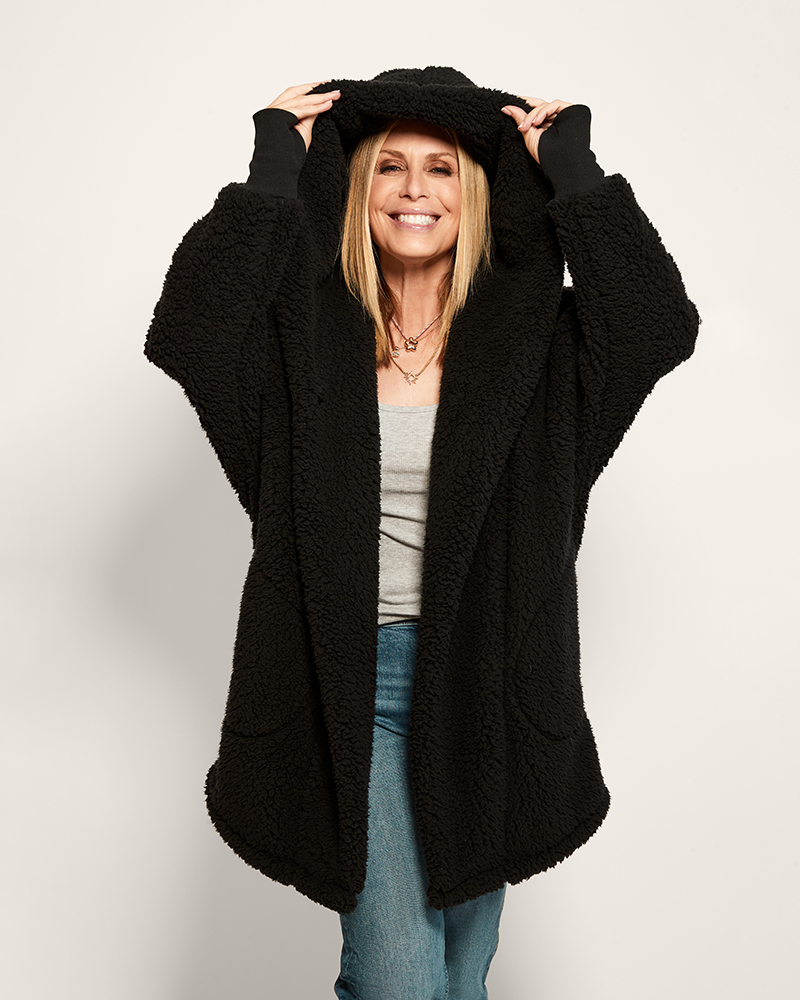 Woman wearing a black sherpa coat with a plain background