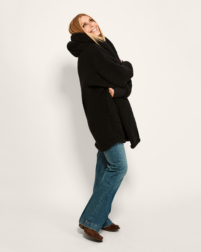 Person wearing a black coat and blue jeans on a white background