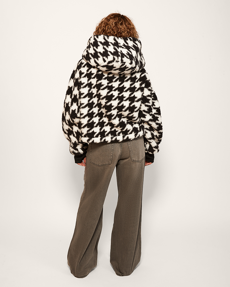 Person wearing a houndstooth pattern jacket on a white background