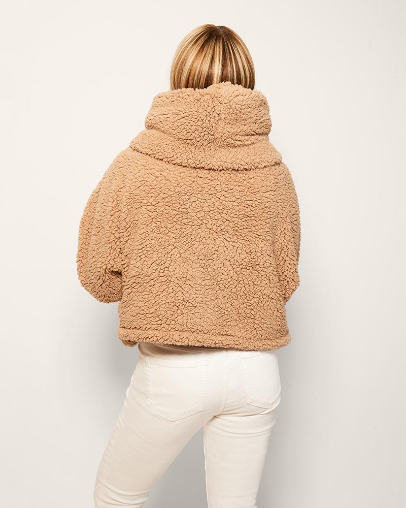 Person wearing a beige sherpa jacket on a plain background