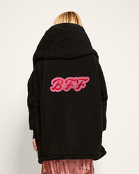 Black coat with 'BFF' text on the back worn by a person against a white background