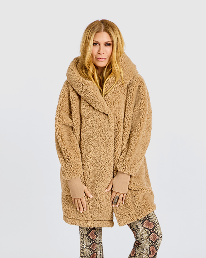 A woman modeling a camel-colored, oversized teddy fleece coat with a wide collar and long sleeves, paired with snakeskin-print leggings, against a light gray studio background.|Jill is 5'6" wearing size XS/S