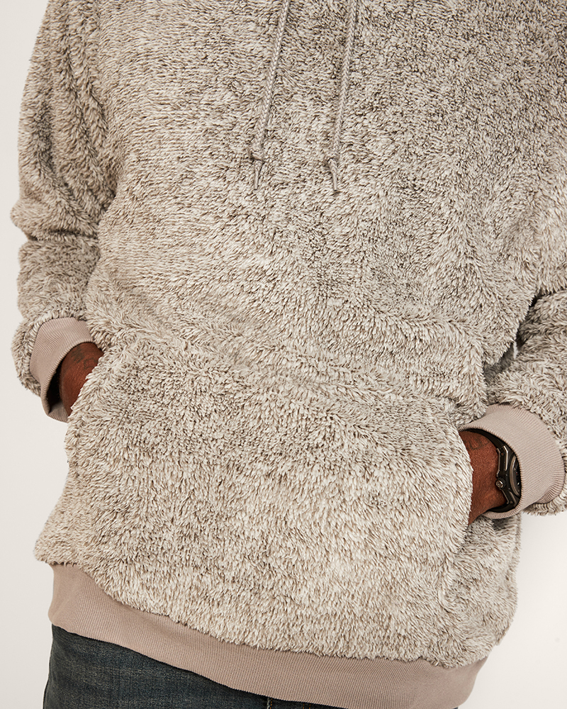 Close-up of a person wearing a textured beige hoodie on a plain background