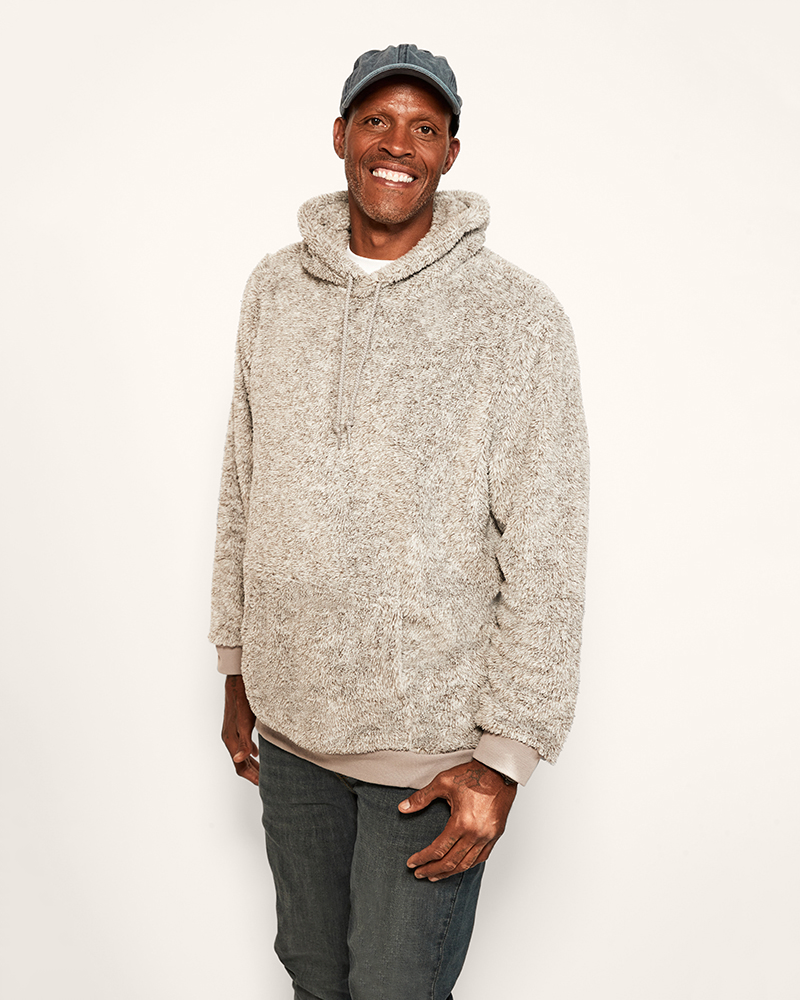 Man wearing a beige hoodie and cap on a white background