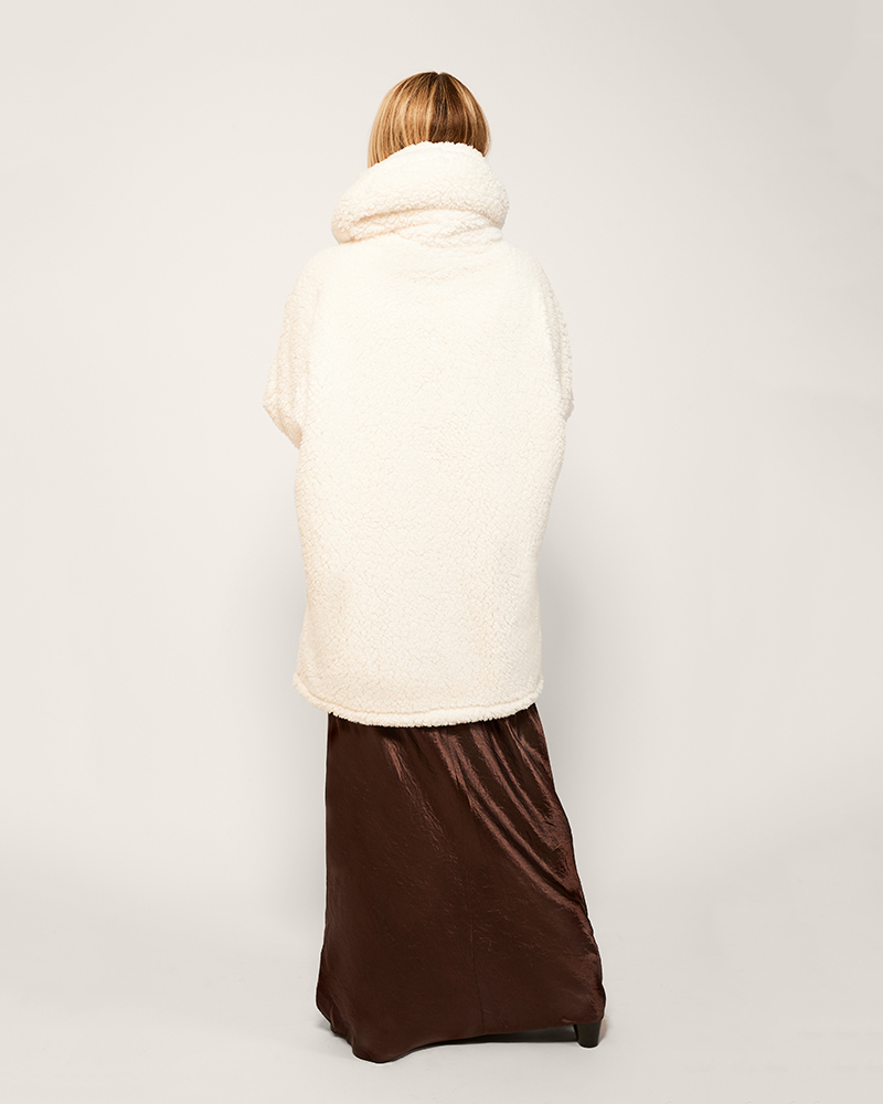 Person wearing a white puffer lounger over a brown skirt on a plain background