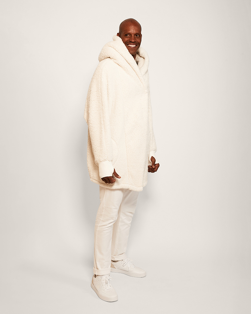 Man wearing a cream-colored sweater and pants on a white background