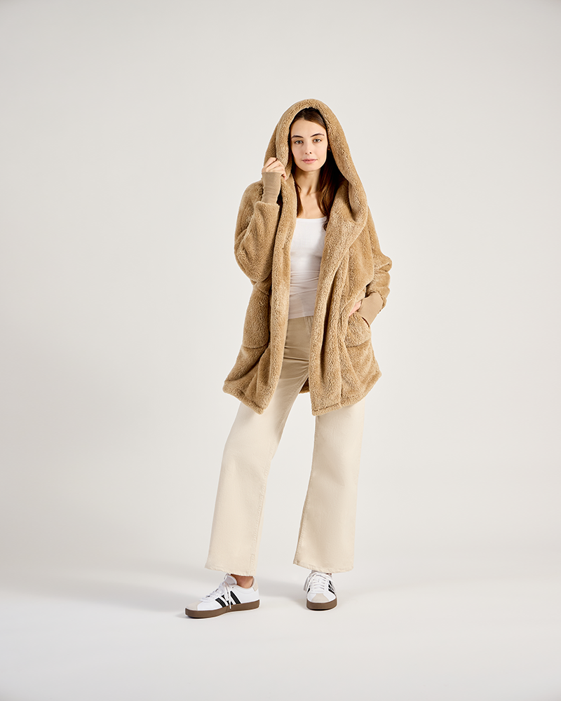 Person wearing a beige hooded cardigan on a white background