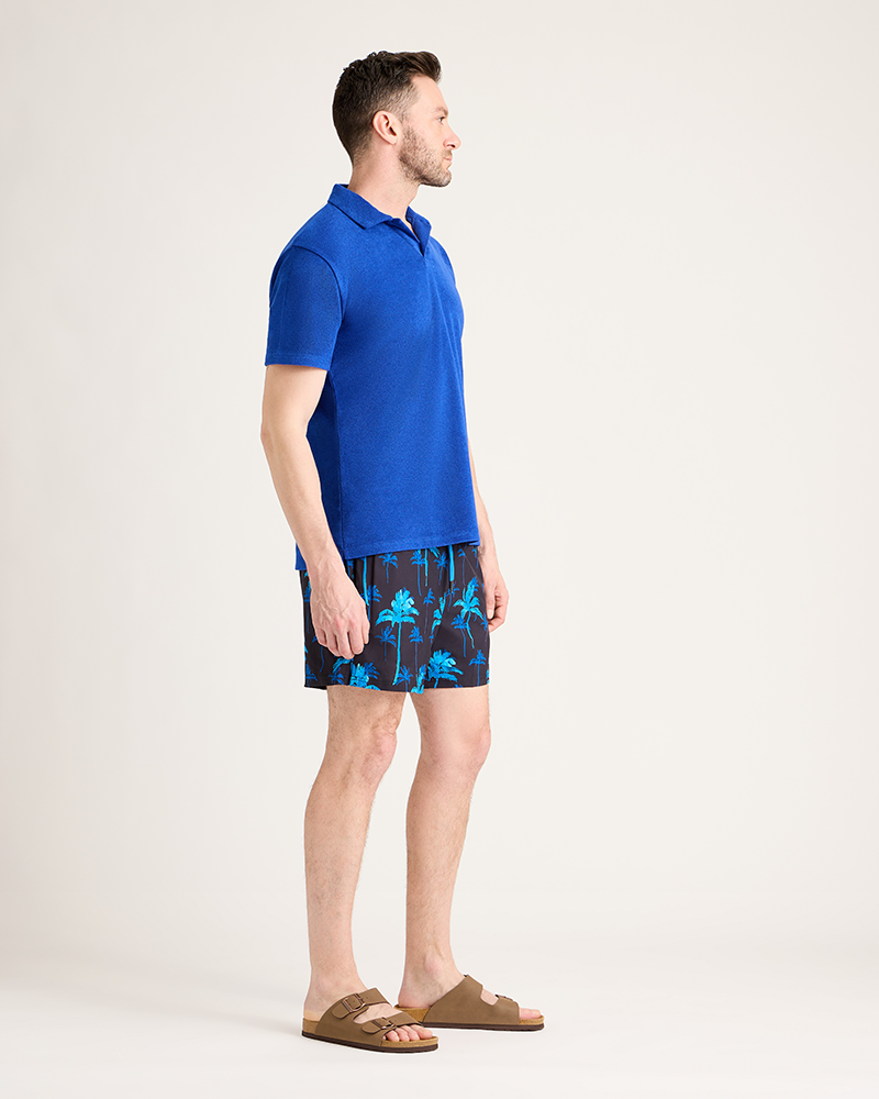 Man wearing a blue polo shirt and patterned shorts on a white background|Model: 5'11" wearing size L