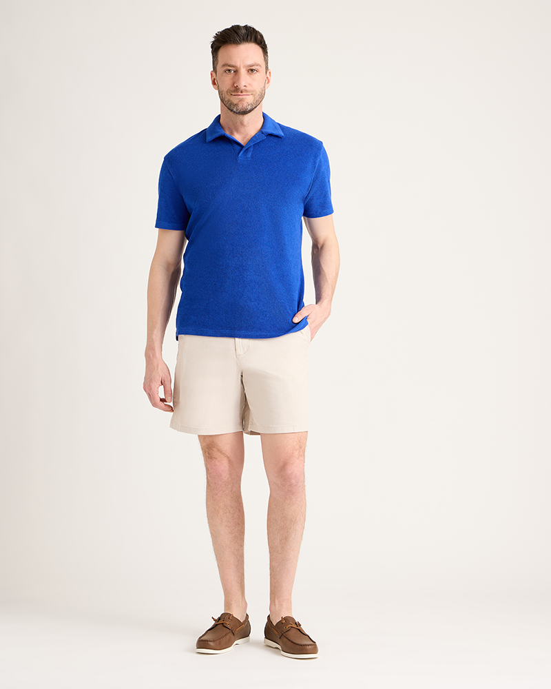 Man wearing a blue polo shirt and beige shorts on a white background|Model: 5'11" wearing size L