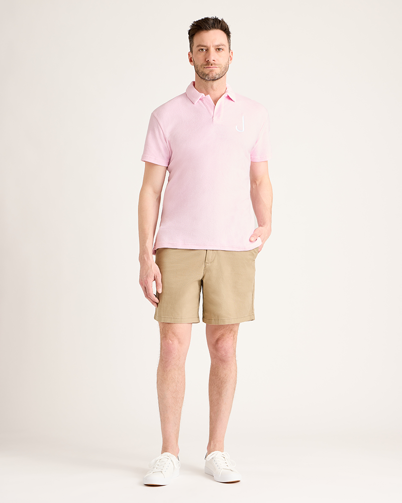 Man wearing a pink polo shirt and beige shorts on a white background|Model: 5'11" wearing size L