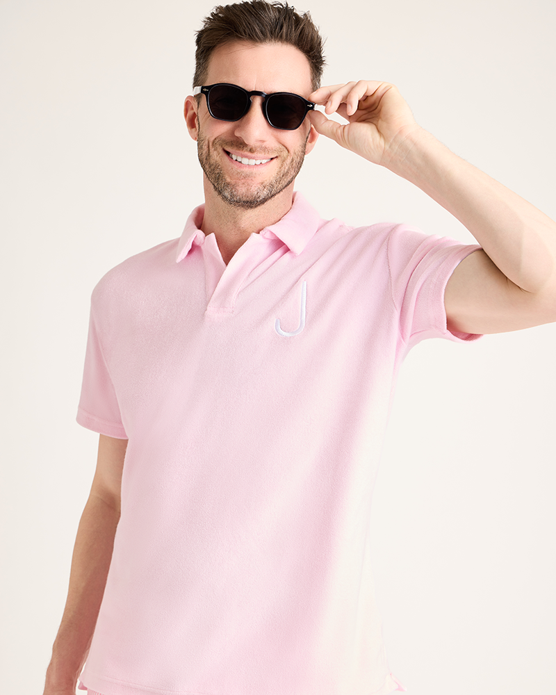 Man wearing a pink polo shirt with a logo on a light background|Model: 5'11" wearing size L